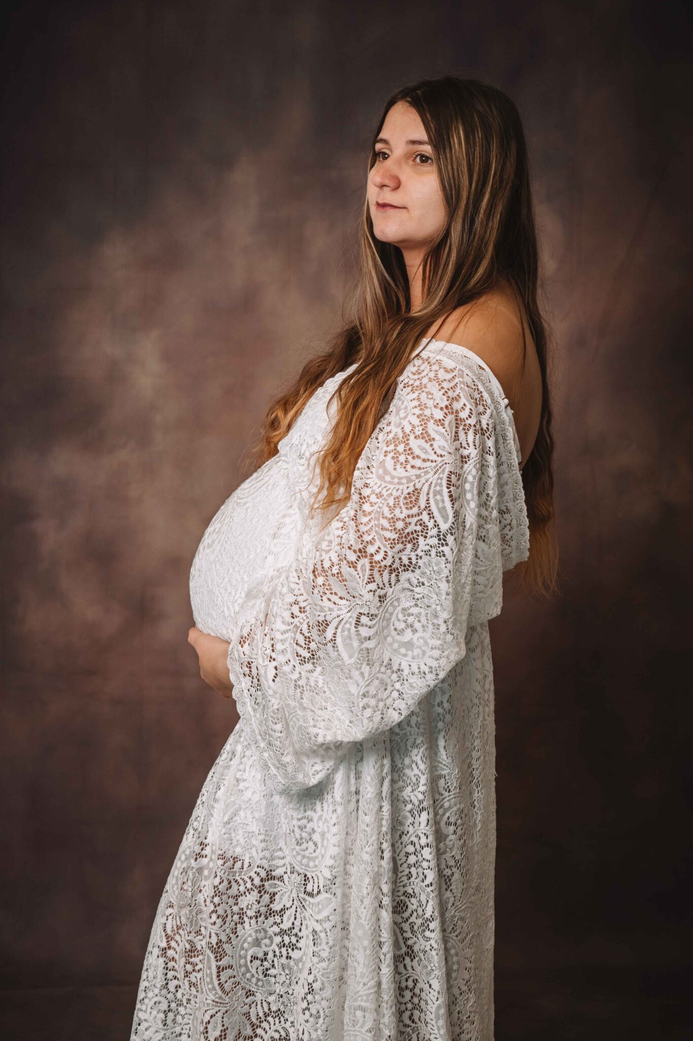 Portrait d'une femme enceinte souriante en studio photo sur fond marron