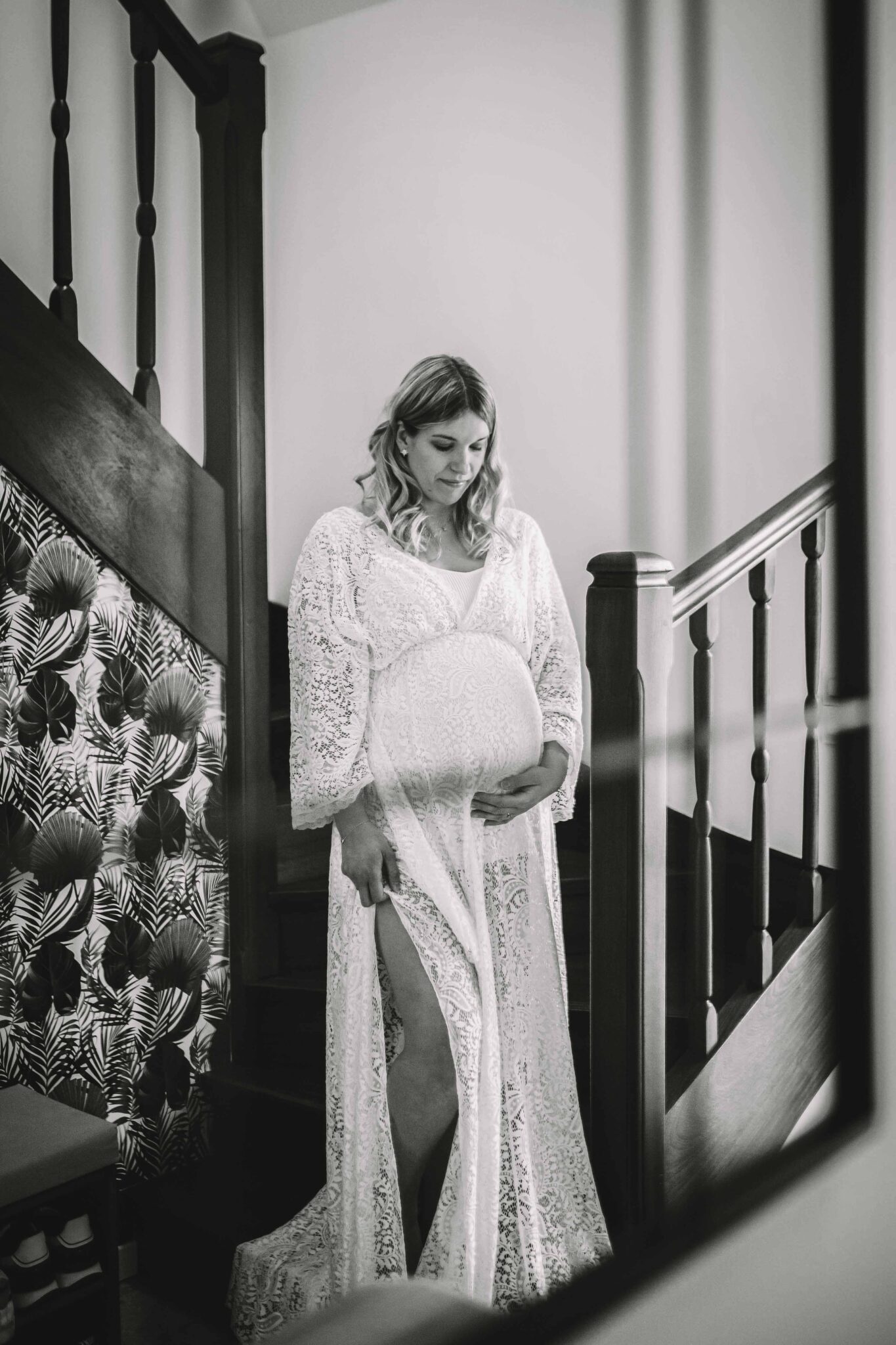 future maman détendue dans un escalier en robe dentelle blanche