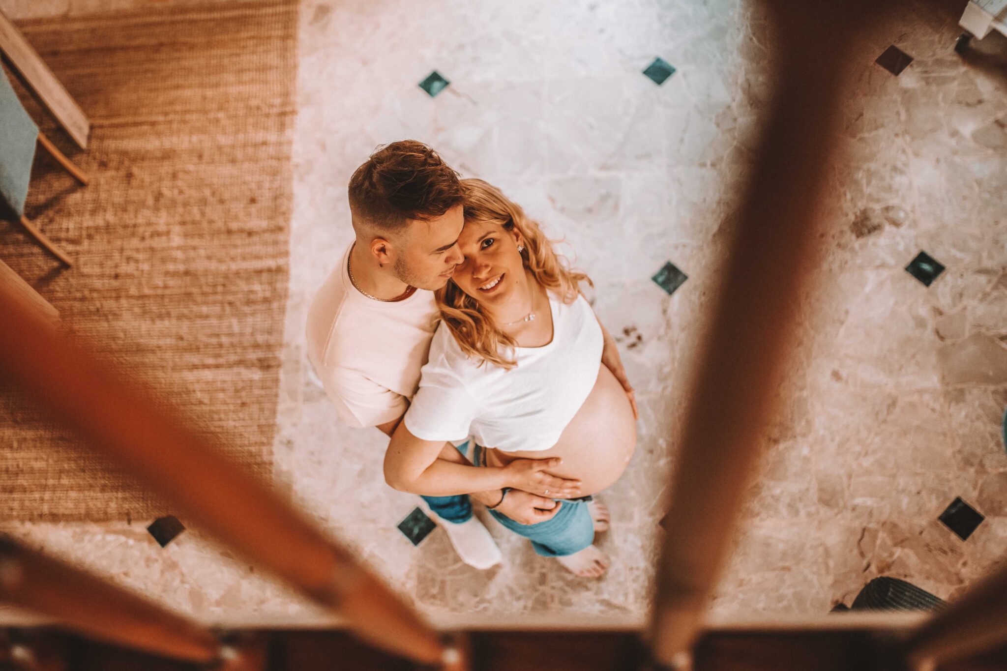 Couple heureux attendant un bébé, pris du haut d'un escalier pendant une séance photo lifestyle
