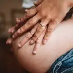 gros plan sur un ventre de grossesse avec les 2 mains du couple posé dessus photographe grossesse Rouen